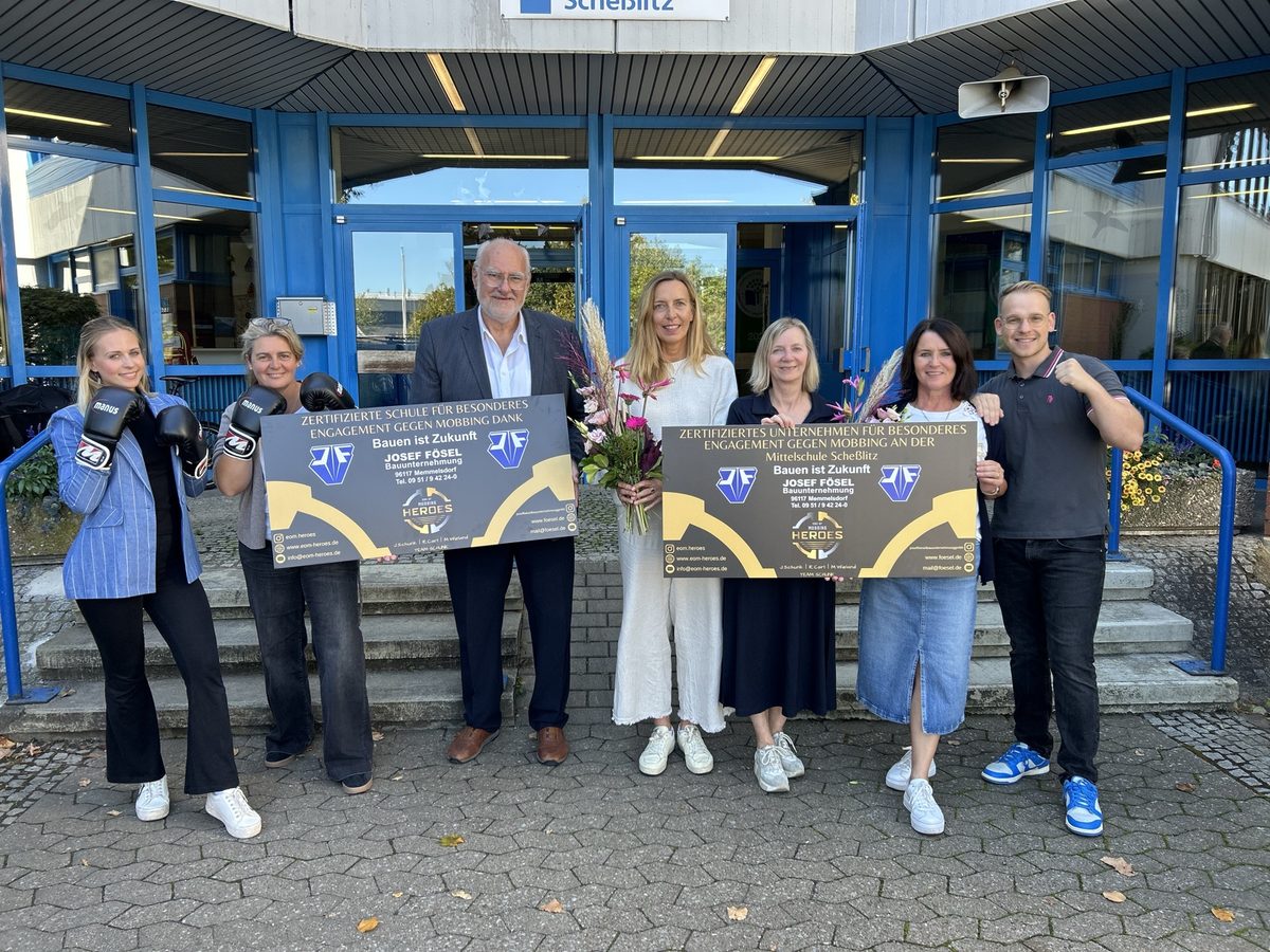 Übergabe an der Mittelschule Scheßlitz: Schulleitung, Vertreter der Bauunternehmung Josef Fösel und das EOM-Team mit zwei Zertifikatstafeln vor dem Schulgebäude
