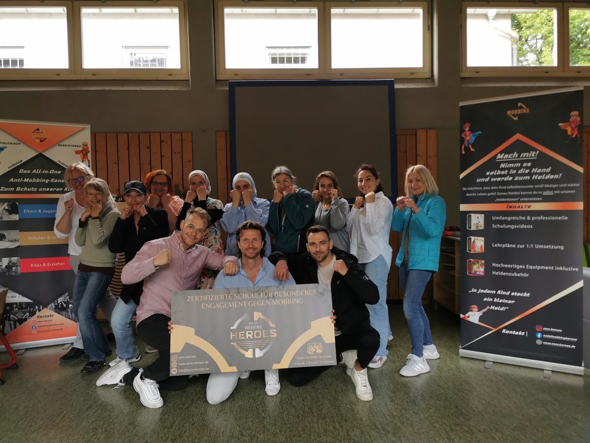 Das Kollegium der Schiller-Grundschule Schweinfurt in Heldenpose mit dem EOM-Team und der Zertifikatstafel