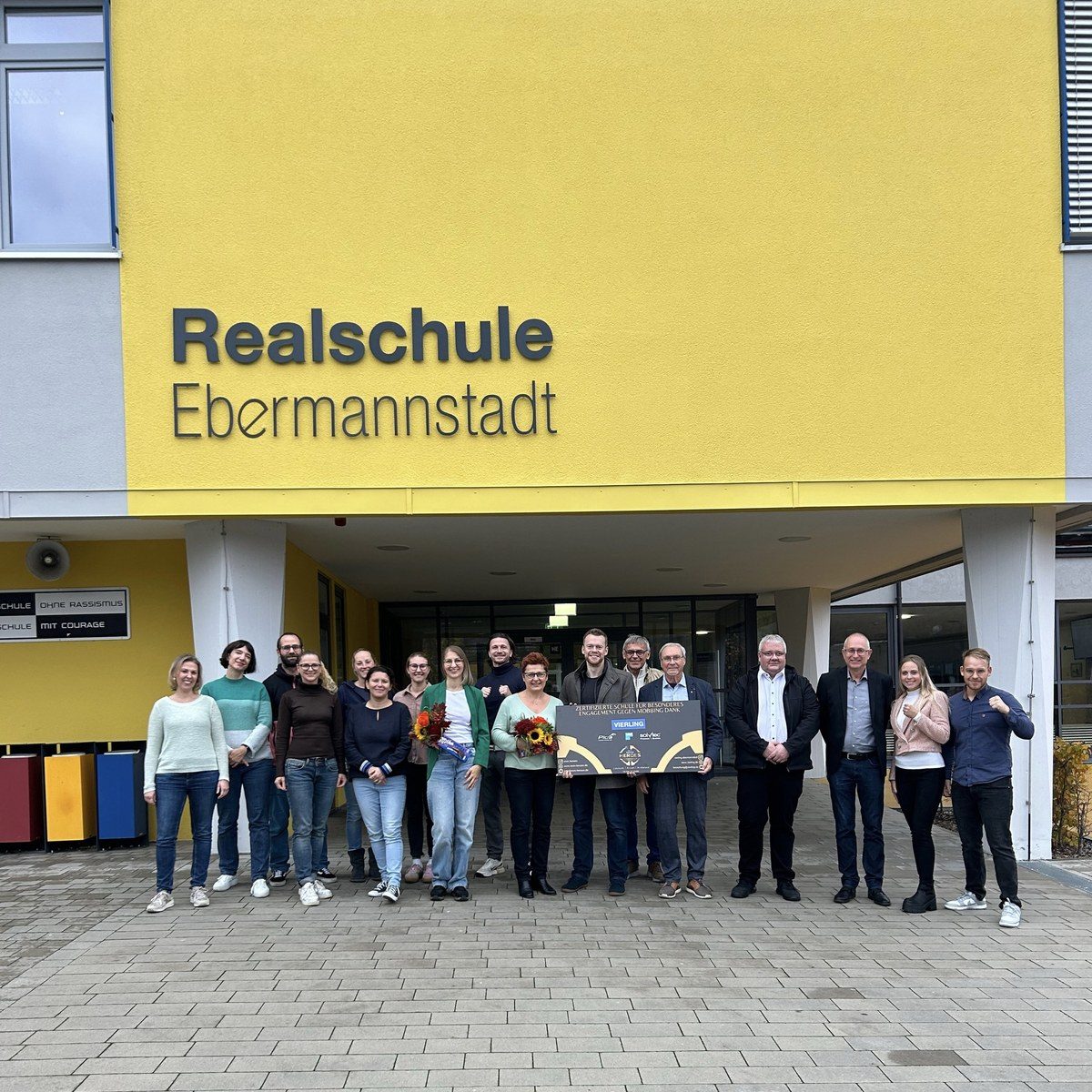 Zertifikatsübergabe vor der Realschule Ebermannstadt: Kollegium, Schulleitung und Firmenvertreter mit dem EOM-Heroes-Schild vor dem Schulgebäude